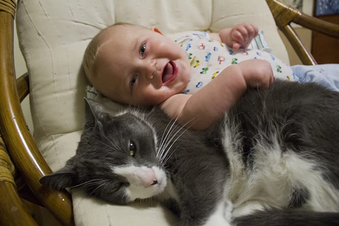 Baby and cat smile for the camera