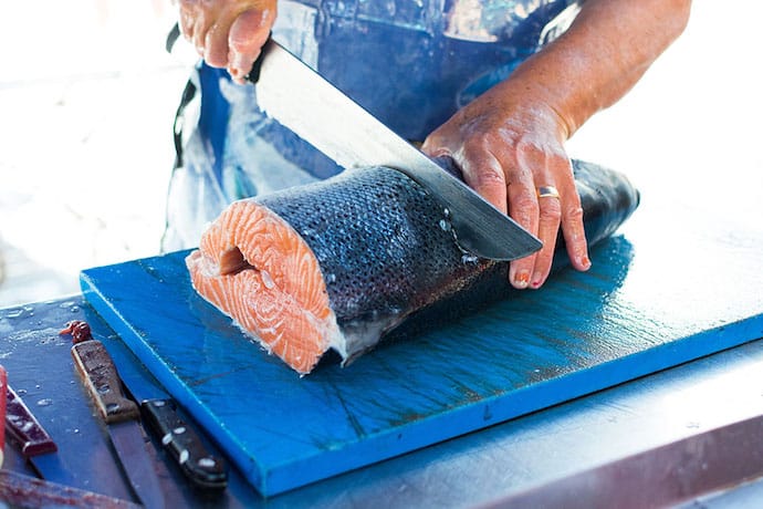 Man's filleting a raw fish on the table
